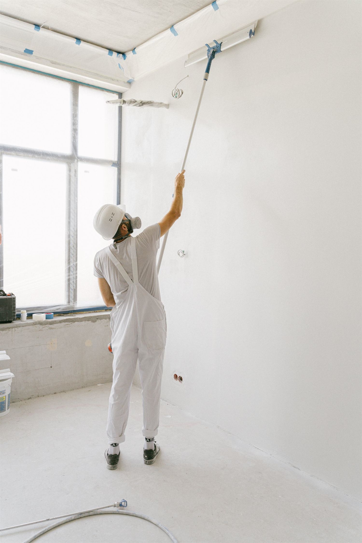 Painter rolling a ceiling in a prepped room
