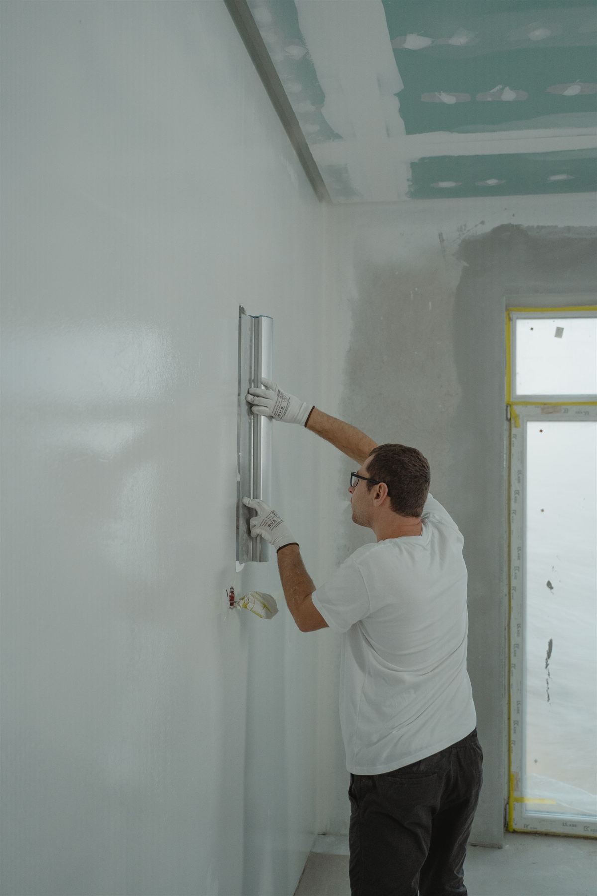 Painter skim-coating drywall